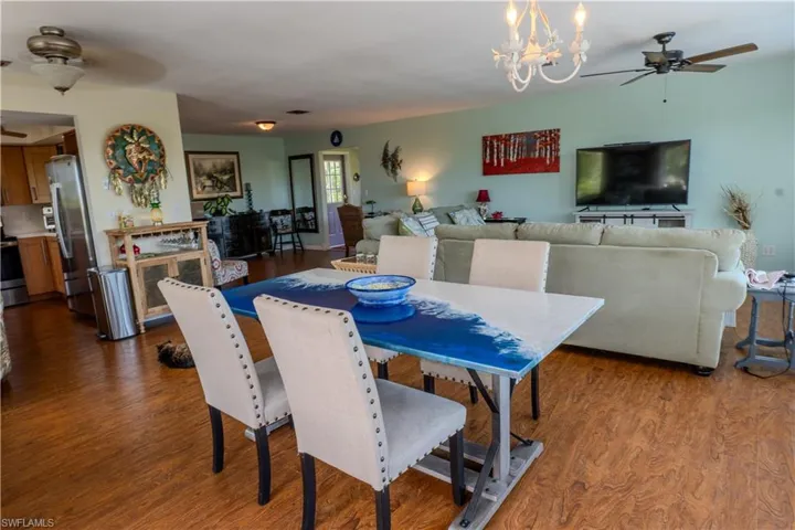 Dining area with ceiling fan, dark wood-style floors, and a chandelier