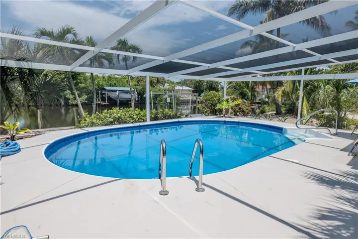 Outdoor pool featuring a patio, glass enclosure, and a water view