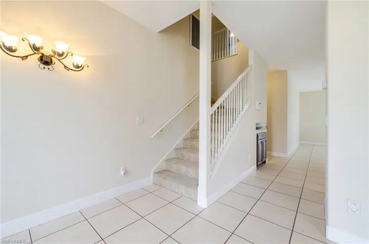 Staircase with tile patterned floors and a high ceiling
