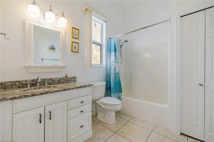 Full bath featuring vanity, shower / bath combo with shower curtain, a closet, and light tile patterned flooring