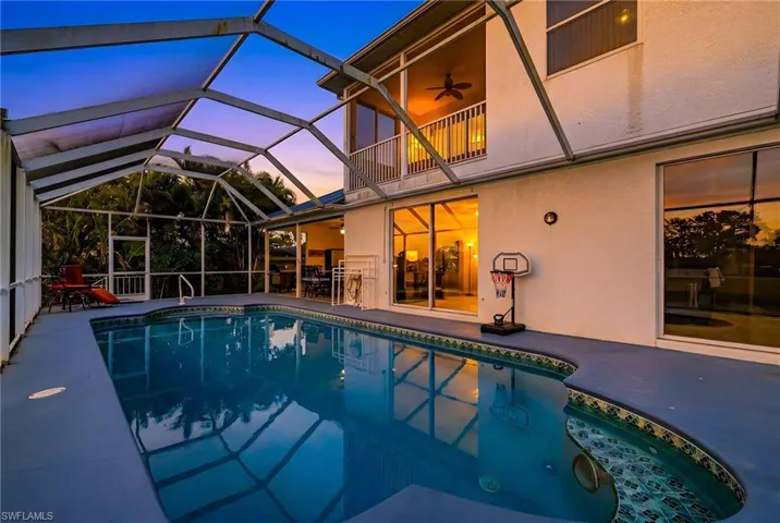 Swimming pool featuring a sunroom, glass enclosure, and a patio area