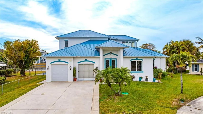 View of front of house featuring a garage, driveway, french doors, stucco siding, and a standing seam roof