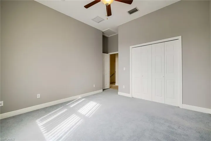 Unfurnished bedroom with light carpet, a ceiling fan, and a closet