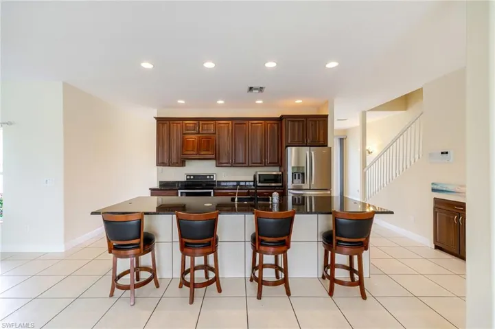 Kitchen with stainless steel appliances, a kitchen bar, recessed lighting, a spacious island, and dark stone counters