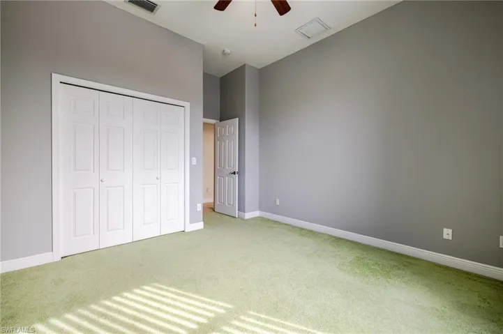 Unfurnished bedroom featuring light carpet, a closet, and a ceiling fan