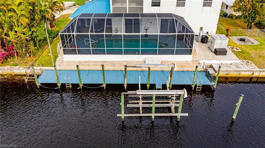 Rear view of property with an outdoor pool, a lanai, a sunroom, a water view, and a fenced backyard