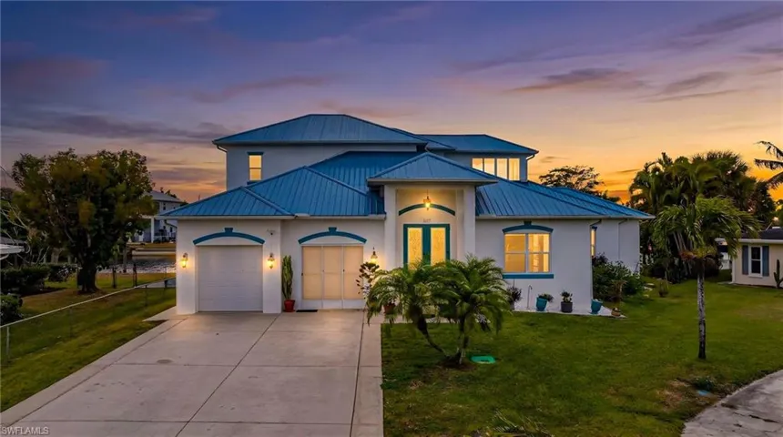 View of front of home with a garage, concrete driveway, stucco siding, and a standing seam roof