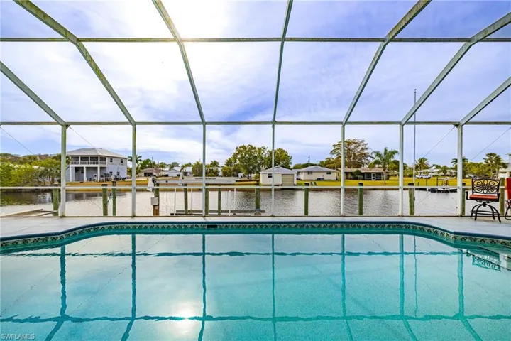 Swimming pool featuring a water view, a residential view, a dock, and a sunroom