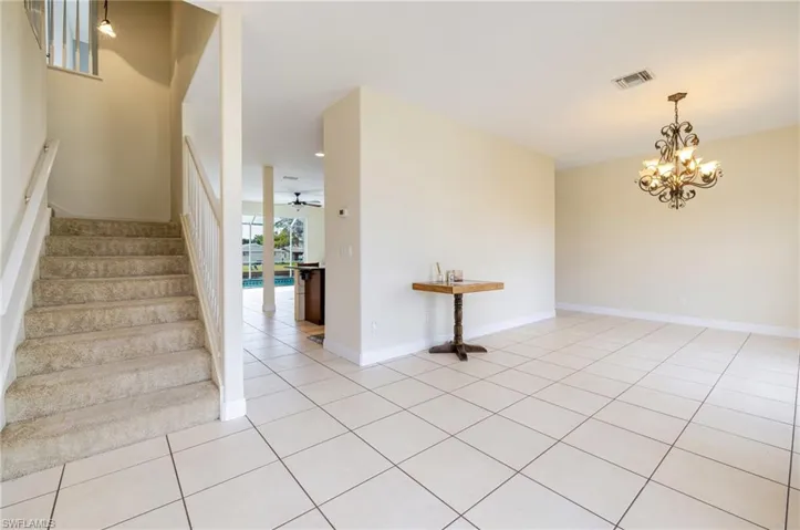 Staircase with tile patterned flooring, a chandelier, and a ceiling fan
