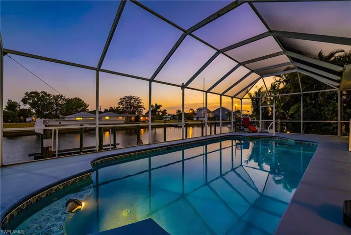 Outdoor pool featuring a sunroom, a lanai, a water view, and a patio area