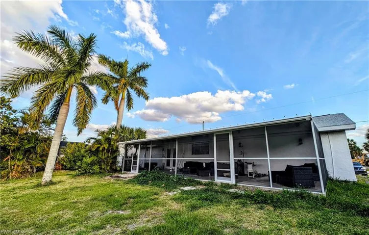 Rear view of property with a yard and a sunroom