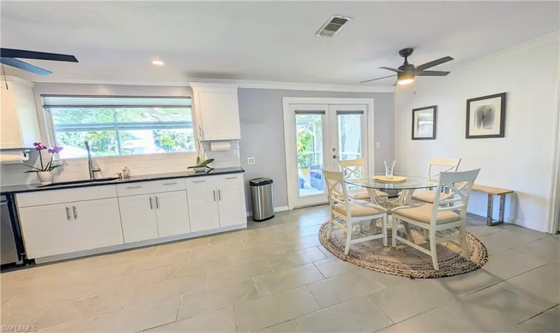 Kitchen featuring ceiling fan, french doors, backsplash, light tile floors, and white cabinets