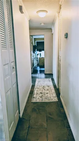 Corridor featuring dark tile flooring, a textured ceiling, and ornamental molding