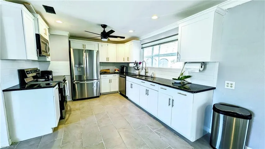 Kitchen featuring white cabinets, appliances with stainless steel finishes, sink, and ceiling fan