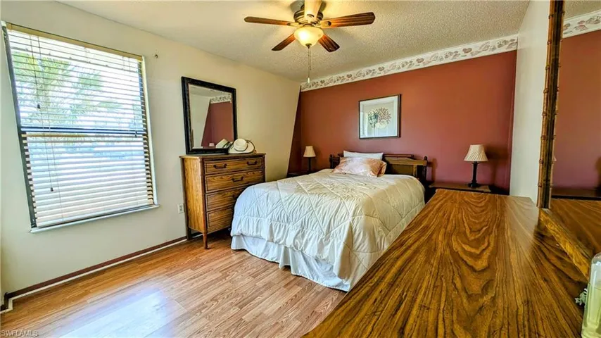 Bedroom with hardwood / wood-style flooring, ceiling fan, and a textured ceiling