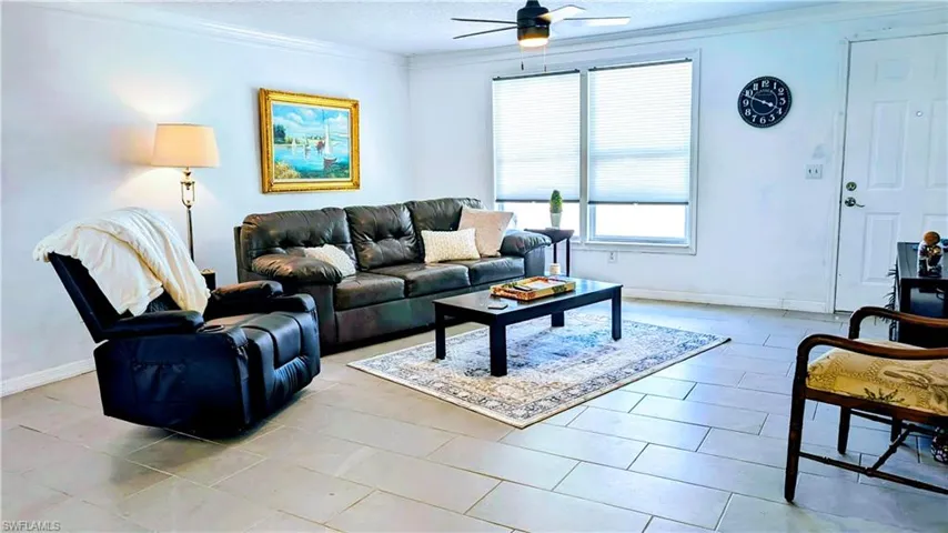 Tiled living room featuring crown molding and ceiling fan