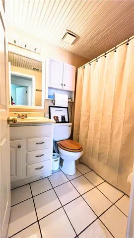 Bathroom with wooden ceiling, tile floors, toilet, and vanity with extensive cabinet space