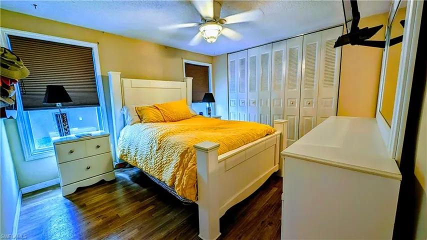 Bedroom featuring a textured ceiling, a closet, ceiling fan, and dark hardwood / wood-style flooring