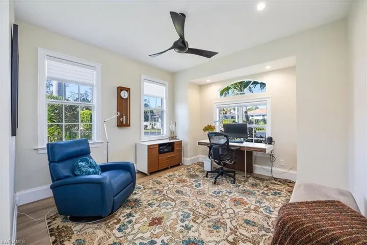Office featuring light wood-type flooring, ceiling fan, and a healthy amount of sunlight