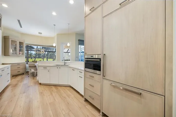 Kitchen with pendant lighting, built in fridge, oven, sink, and light hardwood / wood-style floors