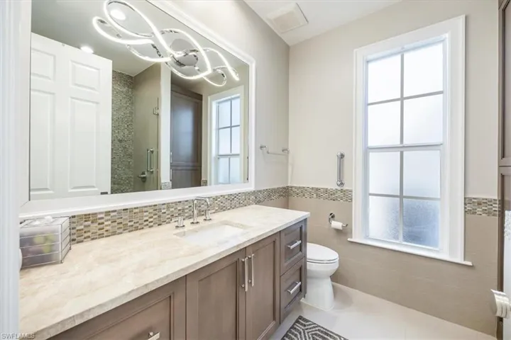Bathroom with walk in shower, tile patterned floors, toilet, vanity, and tile walls