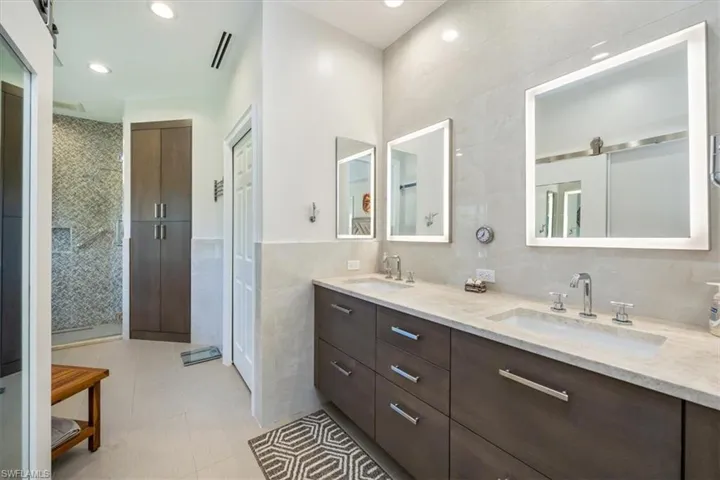 Bathroom featuring tile patterned flooring, vanity, a shower with door, and tile walls