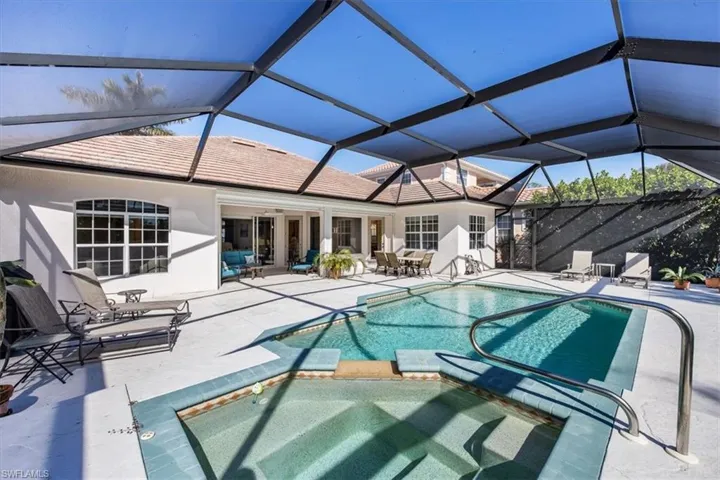View of pool featuring an in ground hot tub, a patio, and glass enclosure