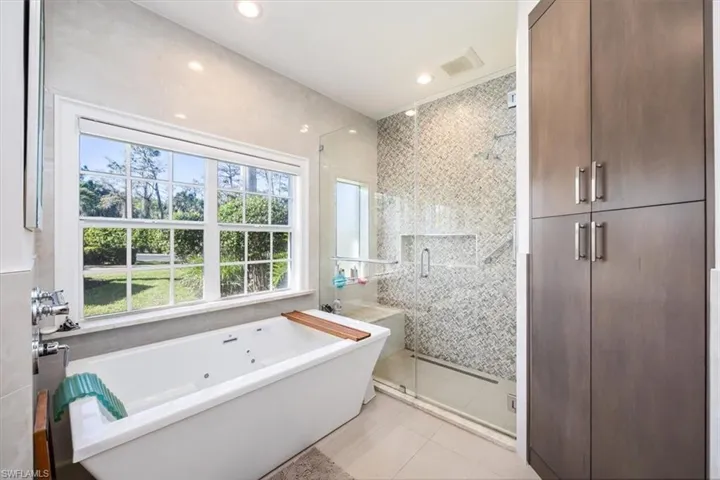 Bathroom with tile patterned floors, a wealth of natural light, independent shower and bath, and tile walls