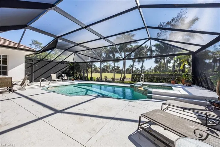 View of pool with an in ground hot tub, a patio, and glass enclosure