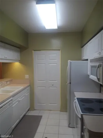 Kitchen with sink, white cabinetry, white appliances, and light tile patterned floors