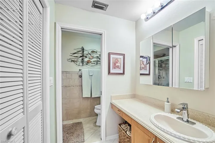 Bathroom featuring a closet, vanity, a shower stall, and light tile patterned flooring