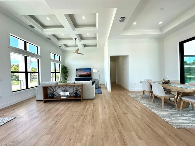 Living area with plenty of natural light, light wood-style flooring, coffered ceiling, and recessed lighting