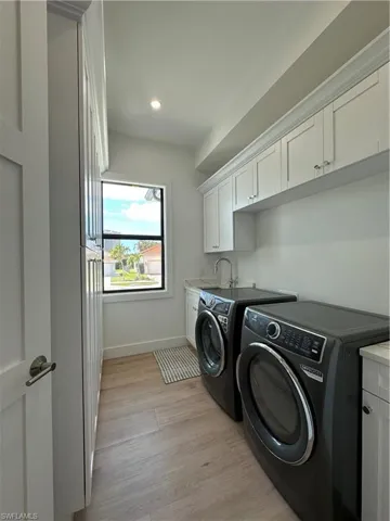 Laundry room with cabinet space, separate washer and dryer, light wood-type flooring, and recessed lighting