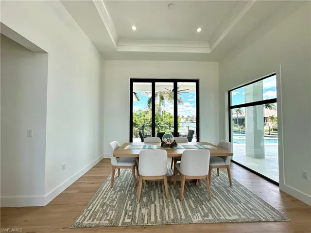Dining room with healthy amount of natural light, light wood-style flooring, a raised ceiling, and recessed lighting