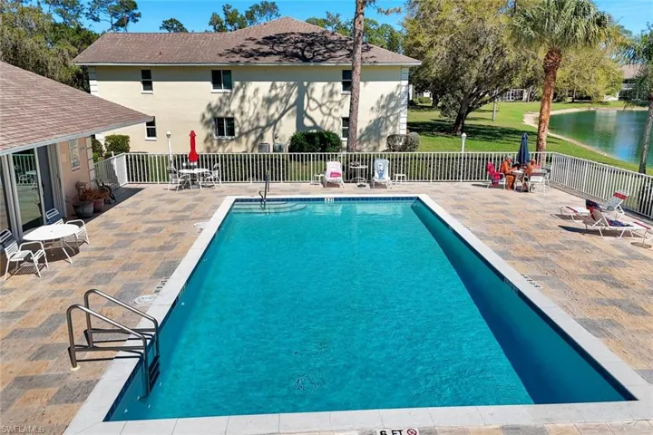 Community pool with a patio, a water view, and fence