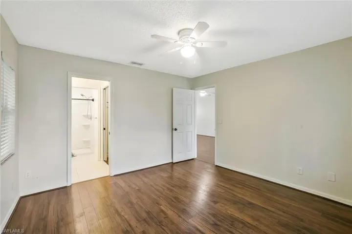 Unfurnished bedroom with baseboards, a textured ceiling, a ceiling fan, visible vents, and wood finished floors