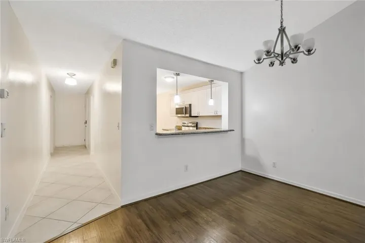 Unfurnished dining area with a chandelier, a textured ceiling, baseboards, and wood finished floors