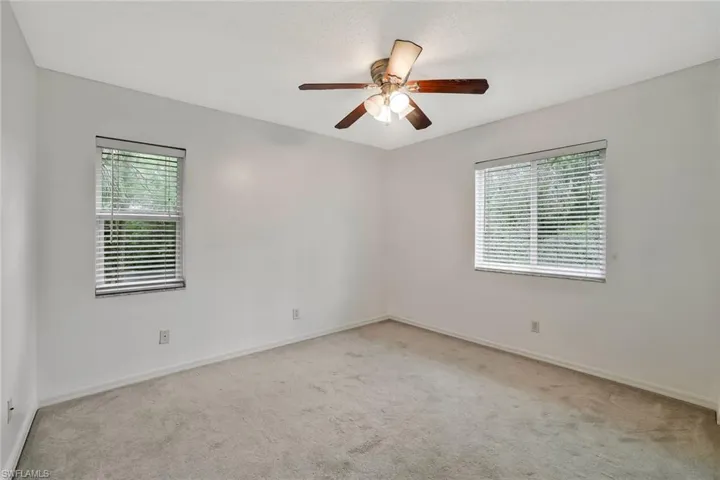 Empty room featuring ceiling fan, plenty of natural light, carpet, and baseboards
