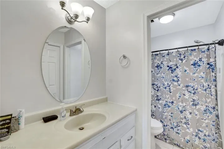 Bathroom with curtained shower, toilet, and vanity