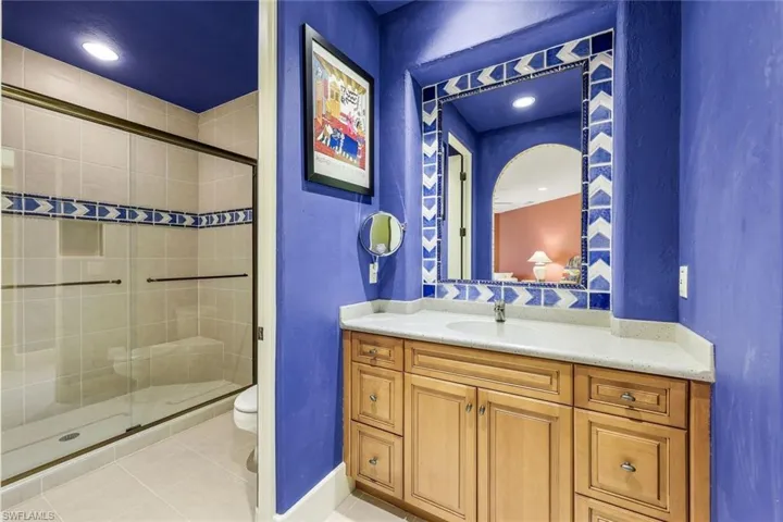 Bathroom featuring tile patterned flooring, vanity, toilet, and an enclosed shower