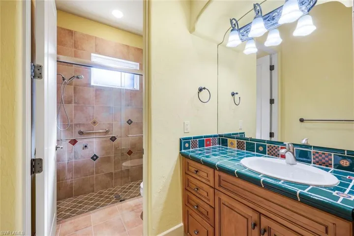 Bathroom with tile patterned flooring, vanity, an enclosed shower, and toilet