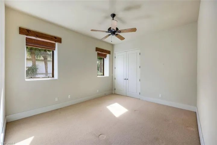 Unfurnished bedroom featuring ceiling fan, a closet, light colored carpet, and multiple windows