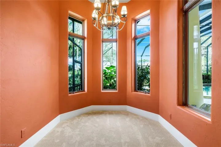 Carpeted empty room featuring a chandelier