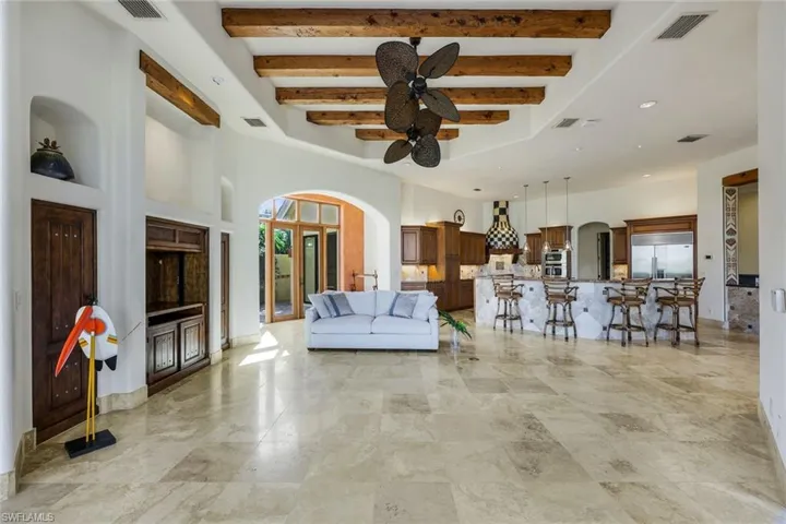 Unfurnished living room featuring beamed ceiling, ceiling fan, and a towering ceiling