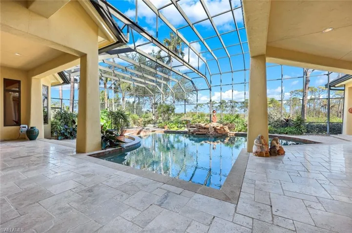 View of swimming pool featuring glass enclosure and a patio