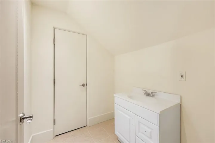 Bathroom with tile patterned floors, vanity, and vaulted ceiling