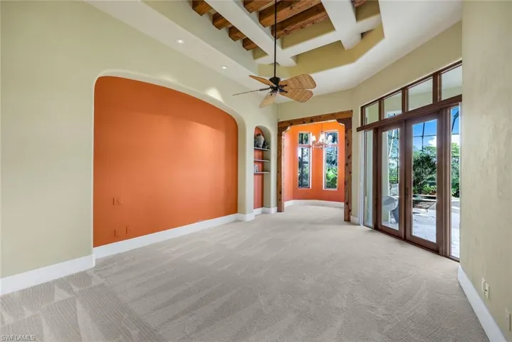Unfurnished room with coffered ceiling, ceiling fan, a towering ceiling, beam ceiling, and light colored carpet