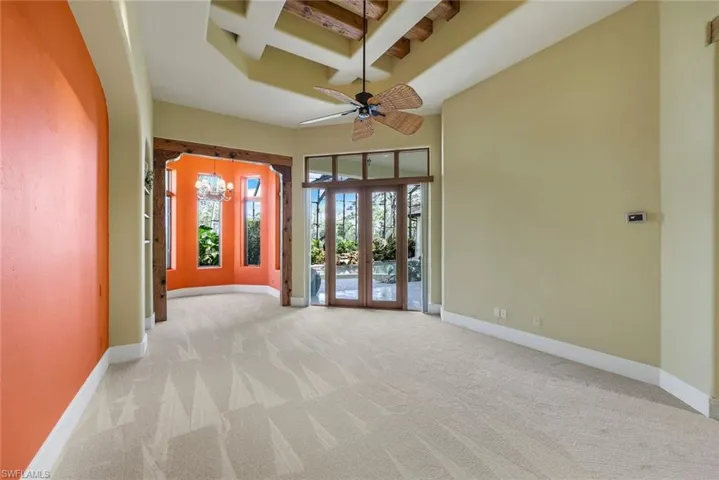 Unfurnished room featuring beam ceiling, ceiling fan, french doors, coffered ceiling, and light colored carpet