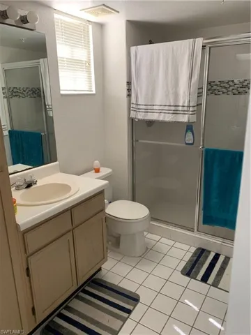 Bathroom with vanity, a shower stall, light tile patterned floors, and a textured wall
