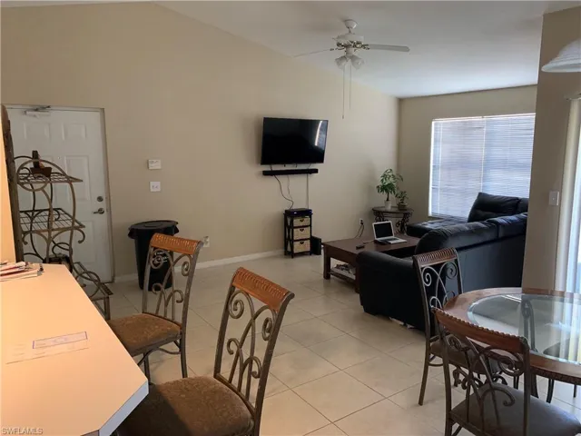 Dining room with lofted ceiling, ceiling fan, and light tile patterned floors